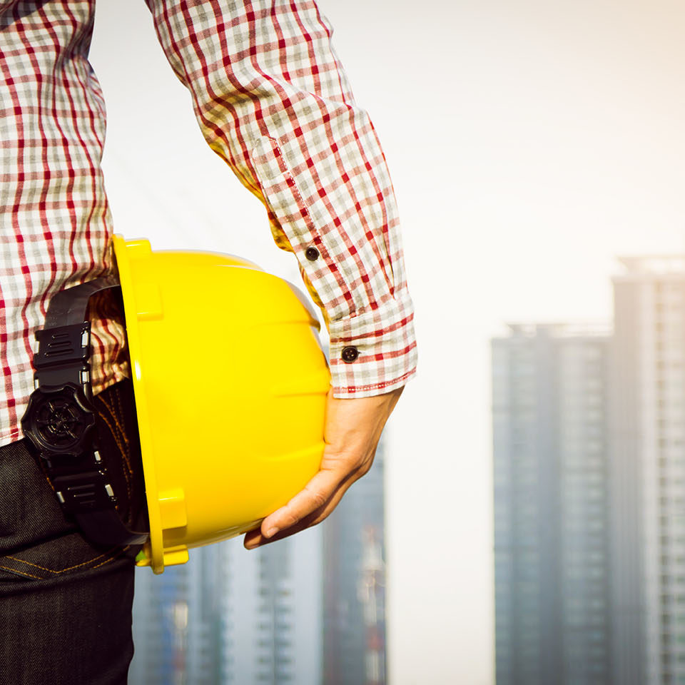 Hand’s engineer worker holding yellow safety helmet with buildin